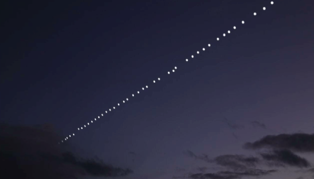 Starlink Un “treno” di satelliti Starlink attraversa il cielo al crepuscolo, apparendo come una lunga sequenza regolare di punti luminosi allineati.
