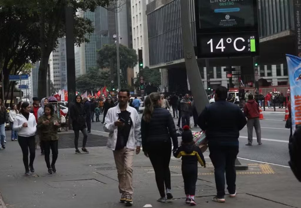 Pessoas saem agasalhadas após temperaturas caírem em São Paulo.