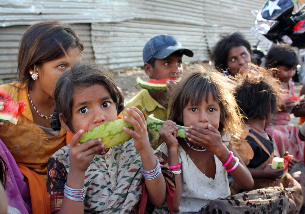 niñas y niños pobres comiendo sandía