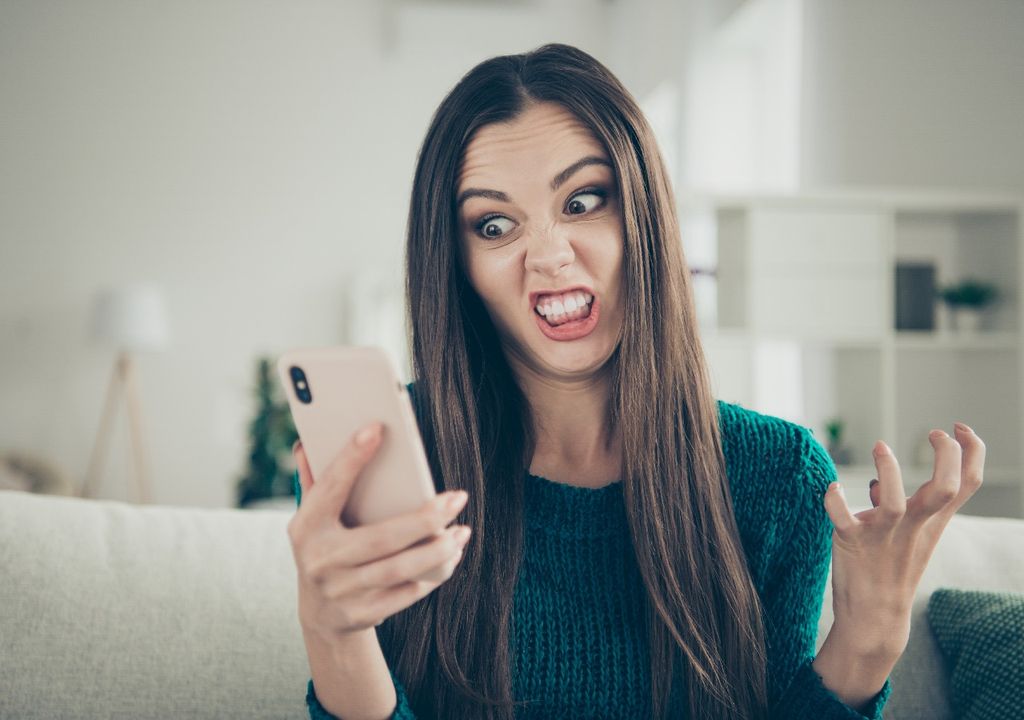 Mujer enojada mirando su celular, fondo interior casa