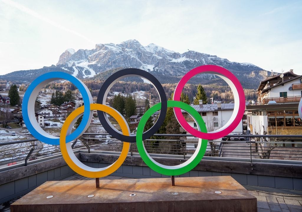 Cortina d'Ampezzo il 12 dicembre 2025, con i 5 cerchi olimpici e sullo sfondo montagne senza neve, tranne le piste innevate artificialmente. Foto Mike Dot - stock.adobe.com