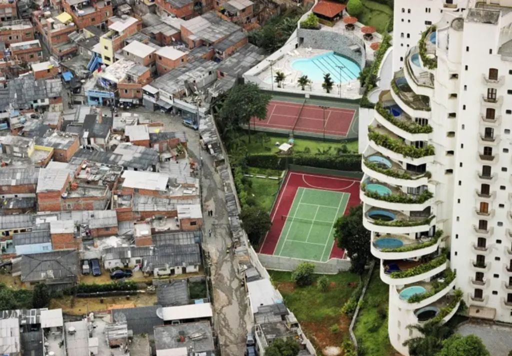 Foto clássica que retrata a desigualdade social em São Paulo (SP), onde a favela Paraisópolis faz divisa com prédios de luxo em bairro nobre. Créditos: Tuca Vieira/Reprodução.