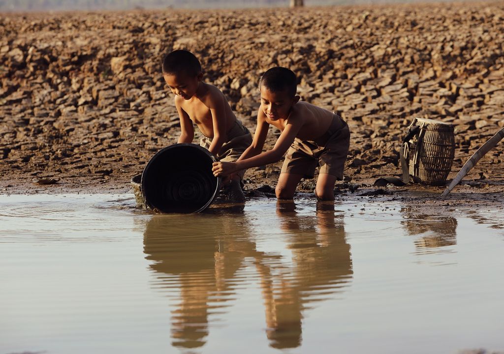 Niños sacando agua de un río; escasez hídrica Niños sacando agua de un río; escasez hídrica