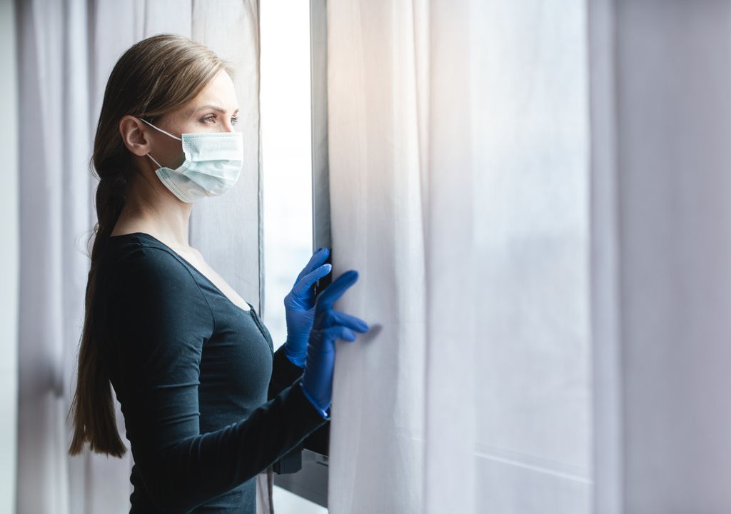 Mulher de máscara abrindo a janela