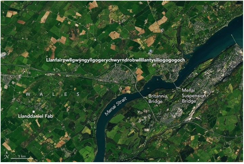 La ciudad galesa, que lleva su nombre desde hace mucho tiempo, aparece como una mancha gris en medio de una imagen bucólica con verdes tierras de cultivo que bordean el estrecho de Menai. Dos puentes marcan una zona conocida por sus traicioneros remolinos. NASA