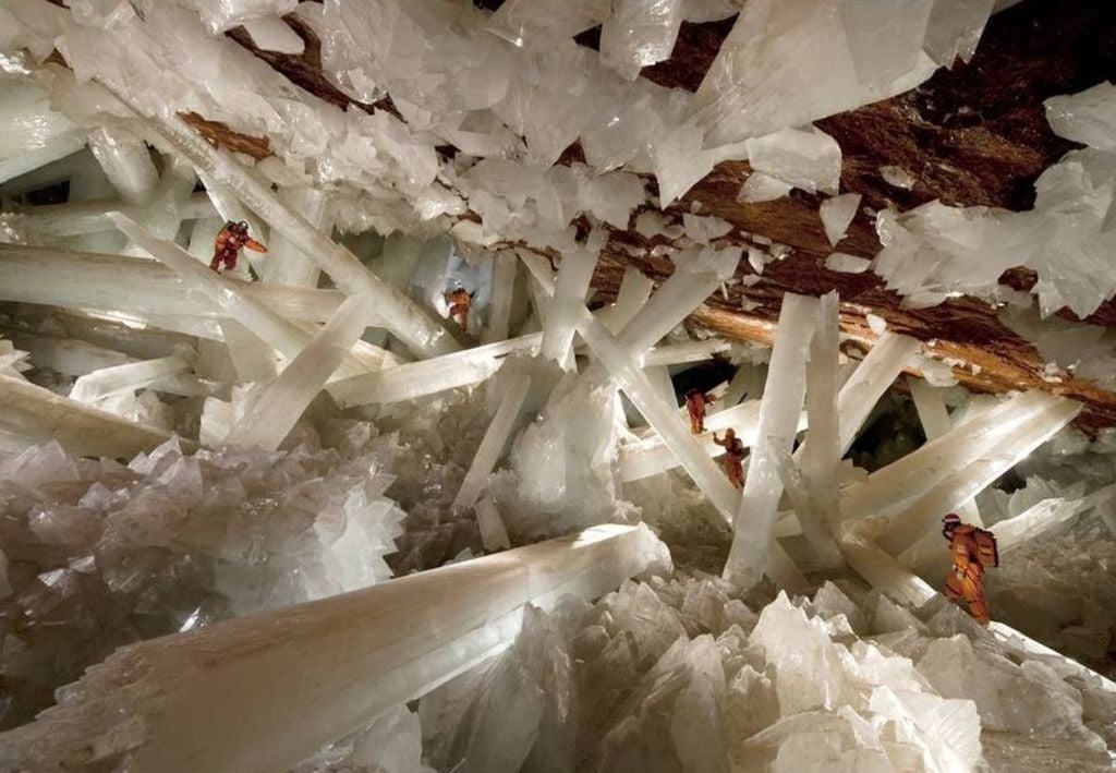 Imagen de personas caminando en medio de un enmarañado de cristales, dentro de una cueva
