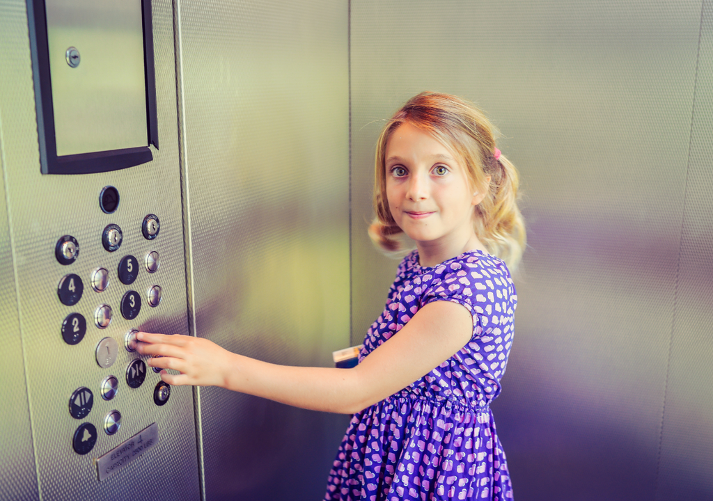 Niña presionando los botones de un ascensor: un gesto cotidiano que permite experimentar cambios reales en la sensación de peso debido a la aceleración.