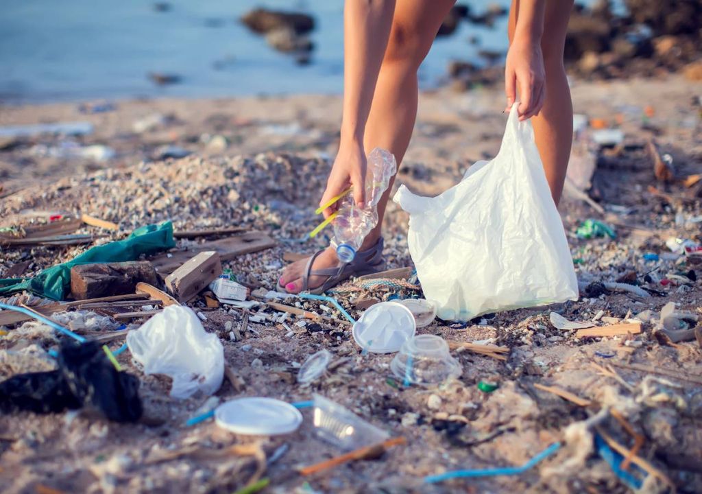Mulher apanha lixo plástico na praia