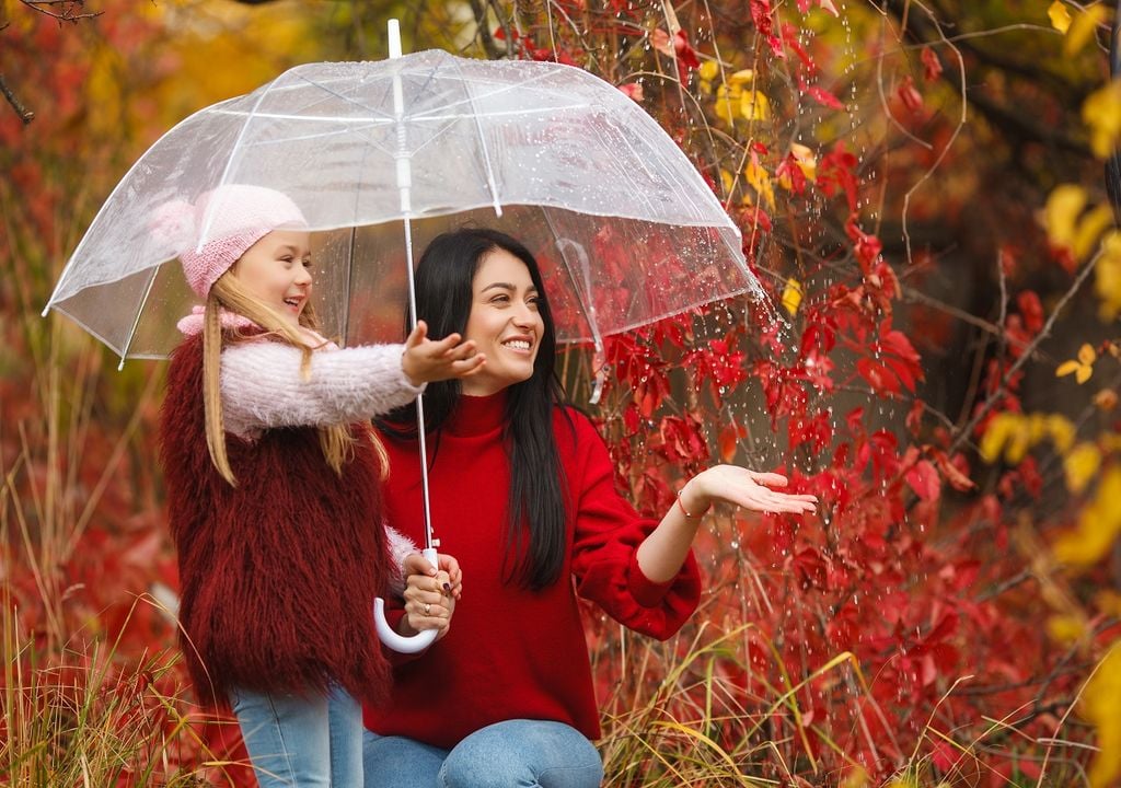 Madre e hija con paraguas transparente fondo otoñal