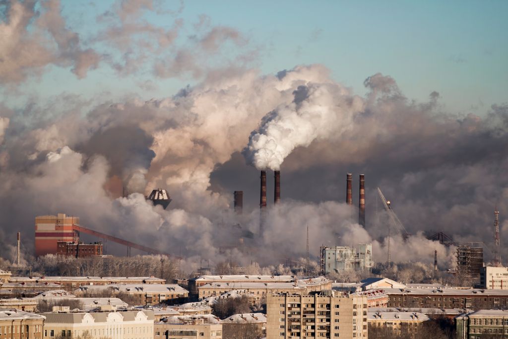industria emitiendo gases y humos cerca de una ciudad