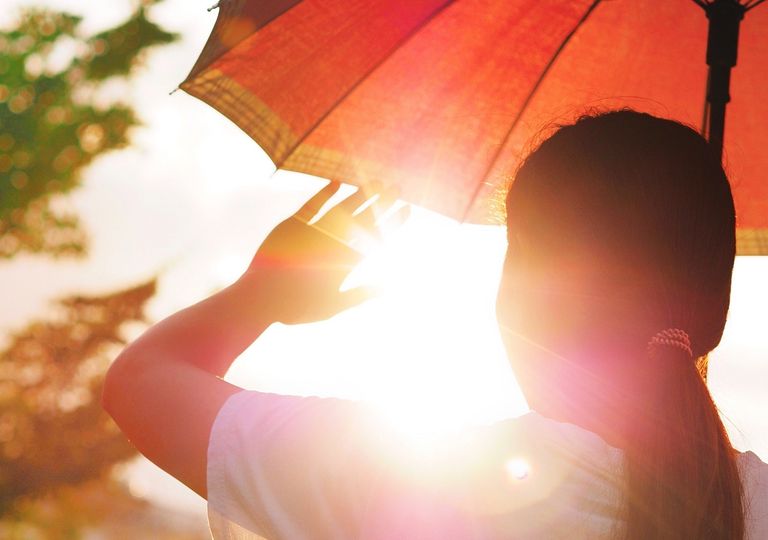 Mujer protegiéndose de los rayos del Sol Mujer protegiéndose de los rayos del Sol