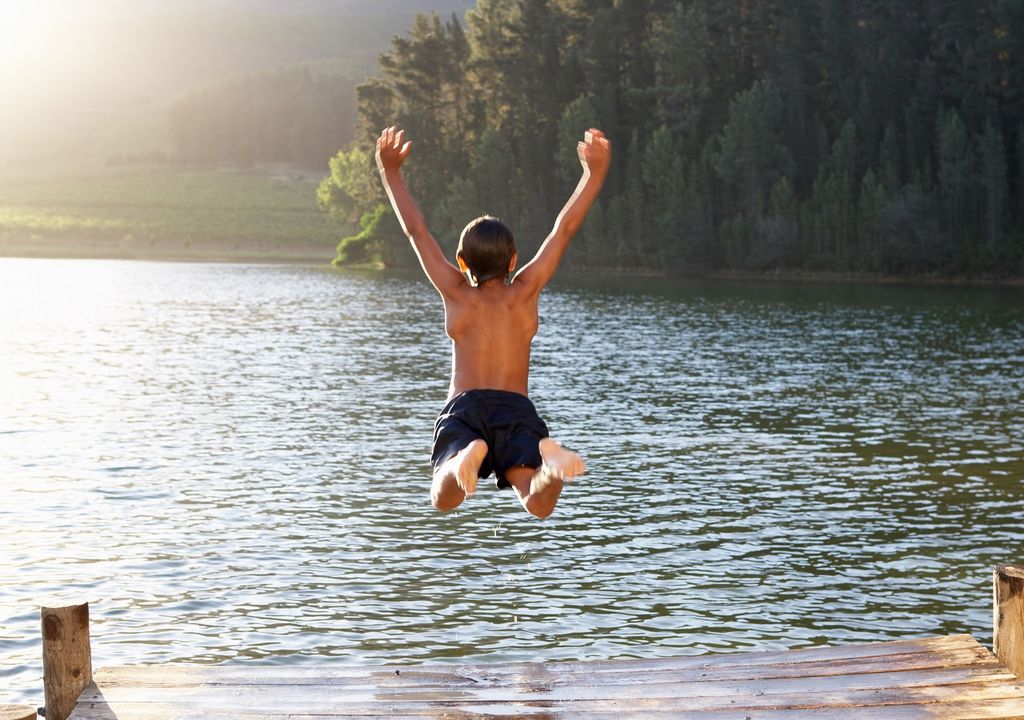 Niño saltando al agua; lago Niño saltando al agua; lago