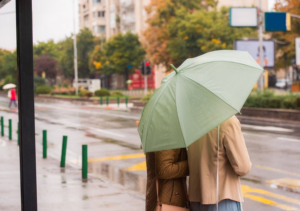 personas con paraguas esperando el bus en día de lluvia