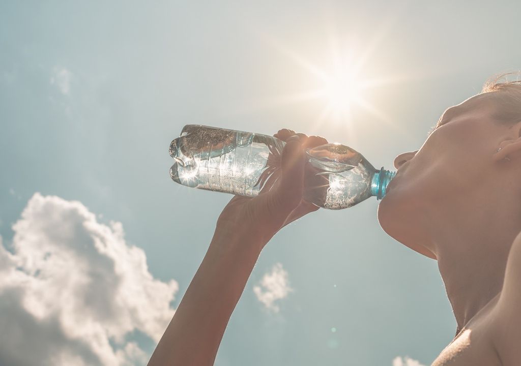 persona bebiendo agua de una botella en un día mayormente soleado