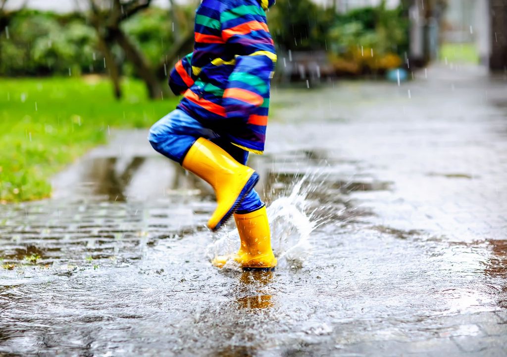 niño jujando en poza de agua bajo la lluvia