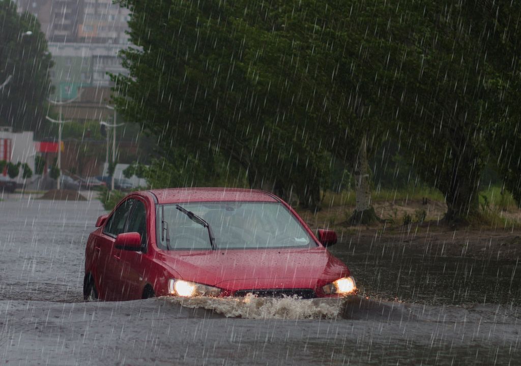 Automóvil transitando por una calle inundada Automóvil transitando por una calle inundada