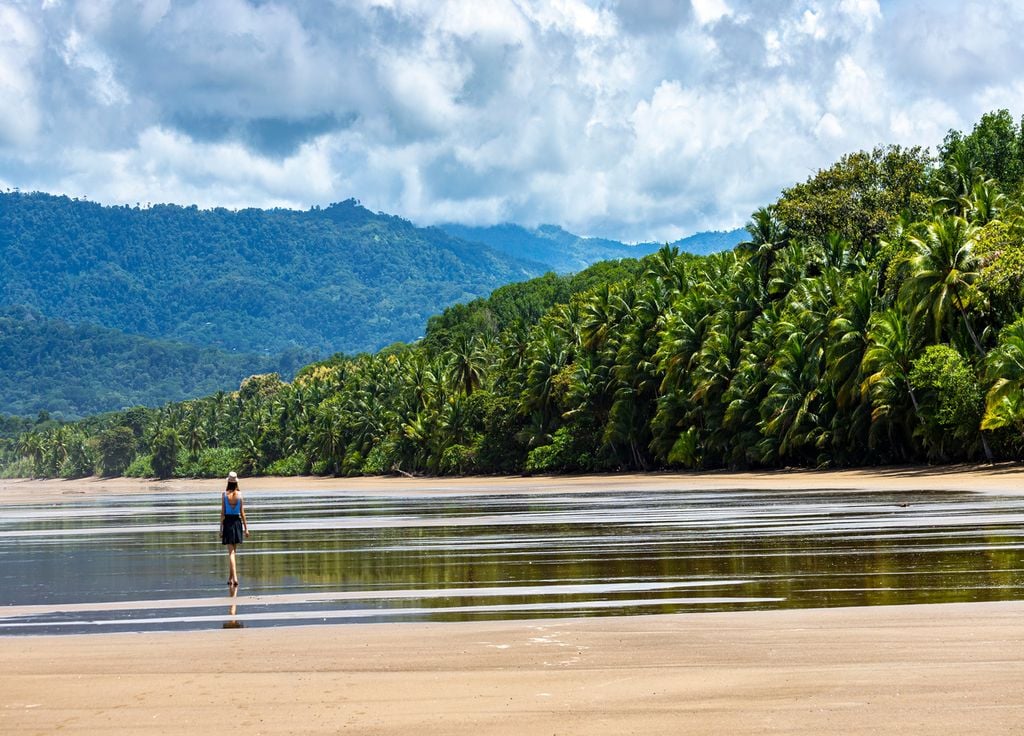 Une jeune fille marche le long d'une plage bordée de palmiers dans le parc national Marino Ballena au Costa Rica.