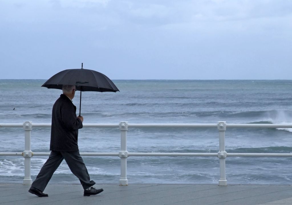 adulto mayor caminando por la costanera en día de lluvia adulto mayor caminando por la costanera en día de lluvia