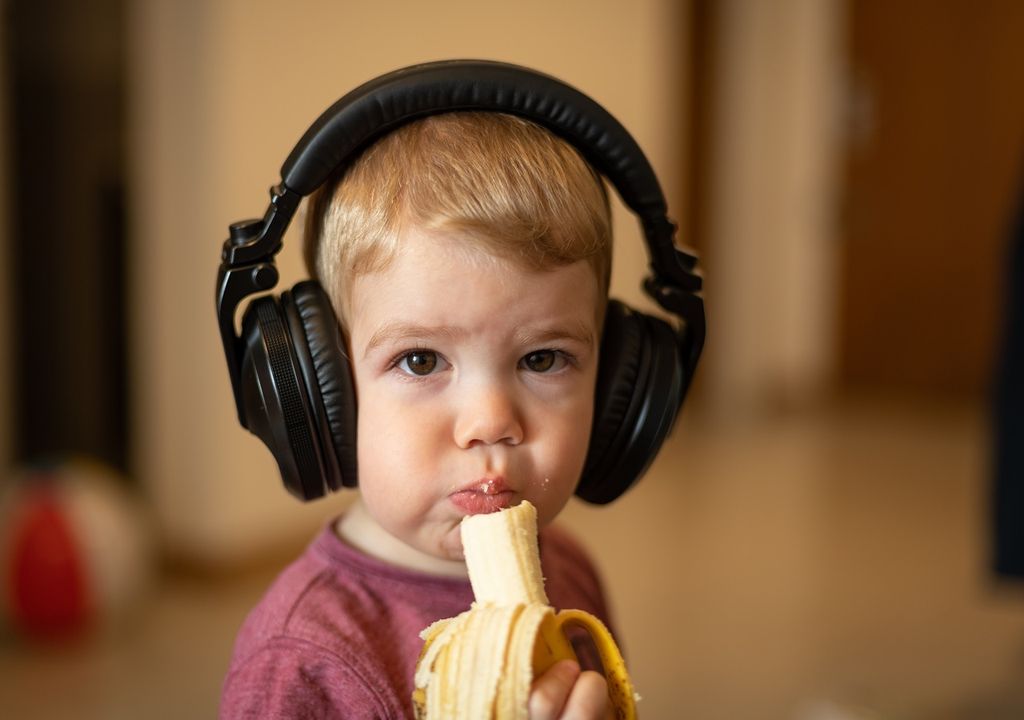Niño con audífonos comiendo plátano