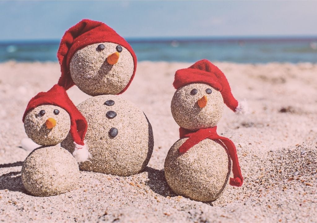 escultura de muñeco de nieve con arena y gorros de navidad