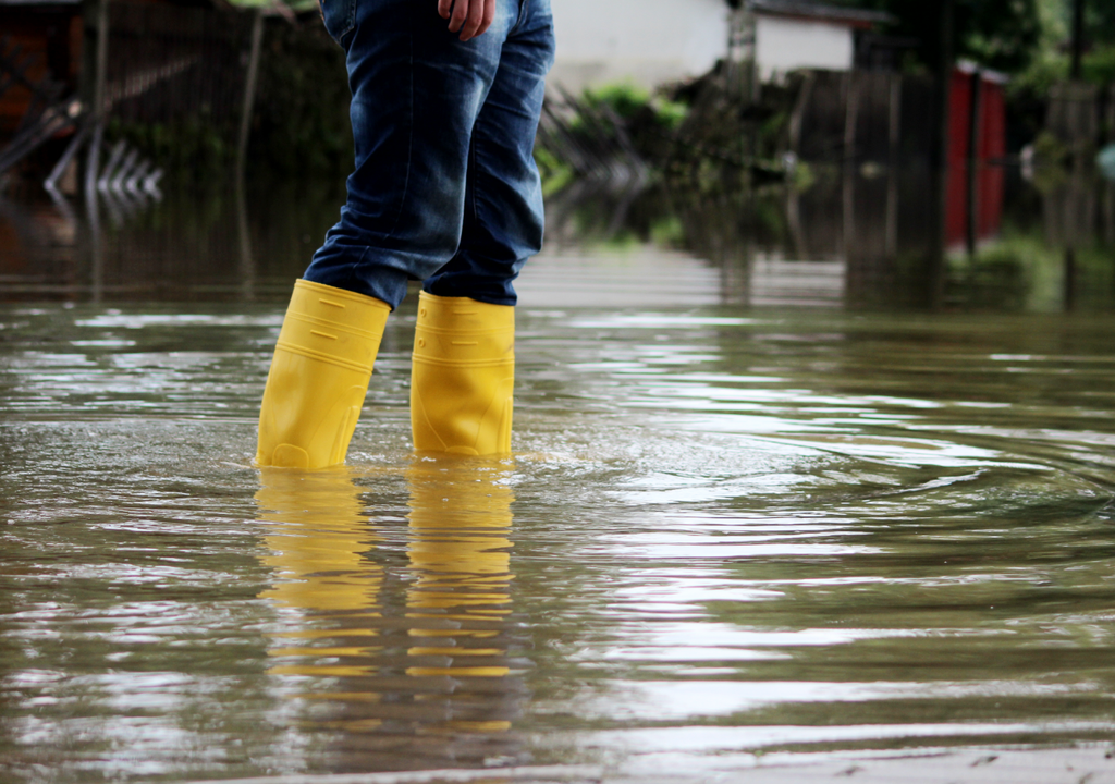 persona de botas en una calle inundada Muchas áreas inundadas por el actual sistema frontal volverán a recibir lluvias durante la próxima semana.