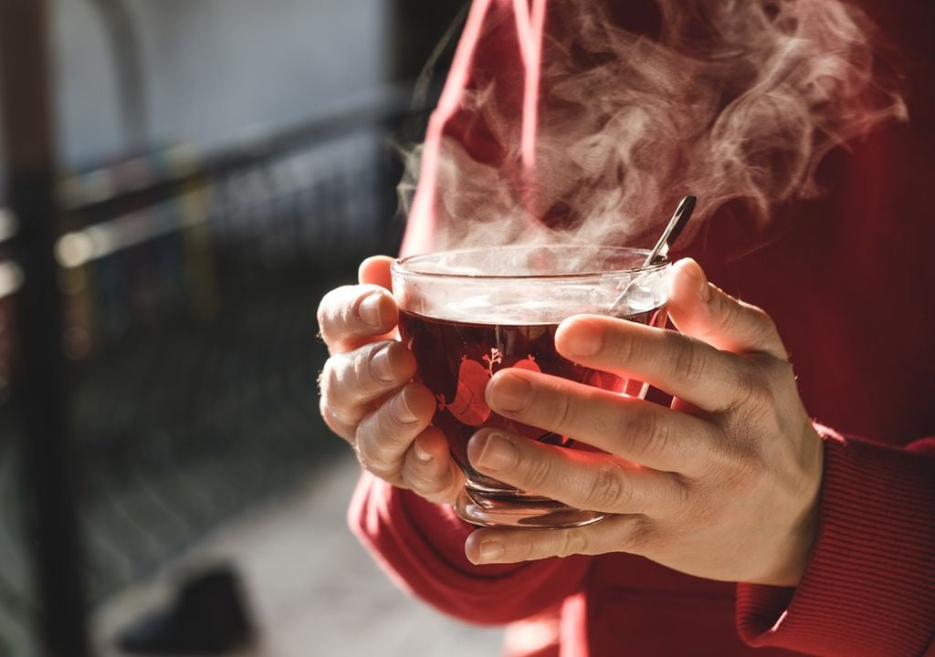 Persona con una taza de té caliente entre sus manos