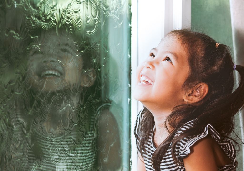 Niña mirando la lluvia por la ventana