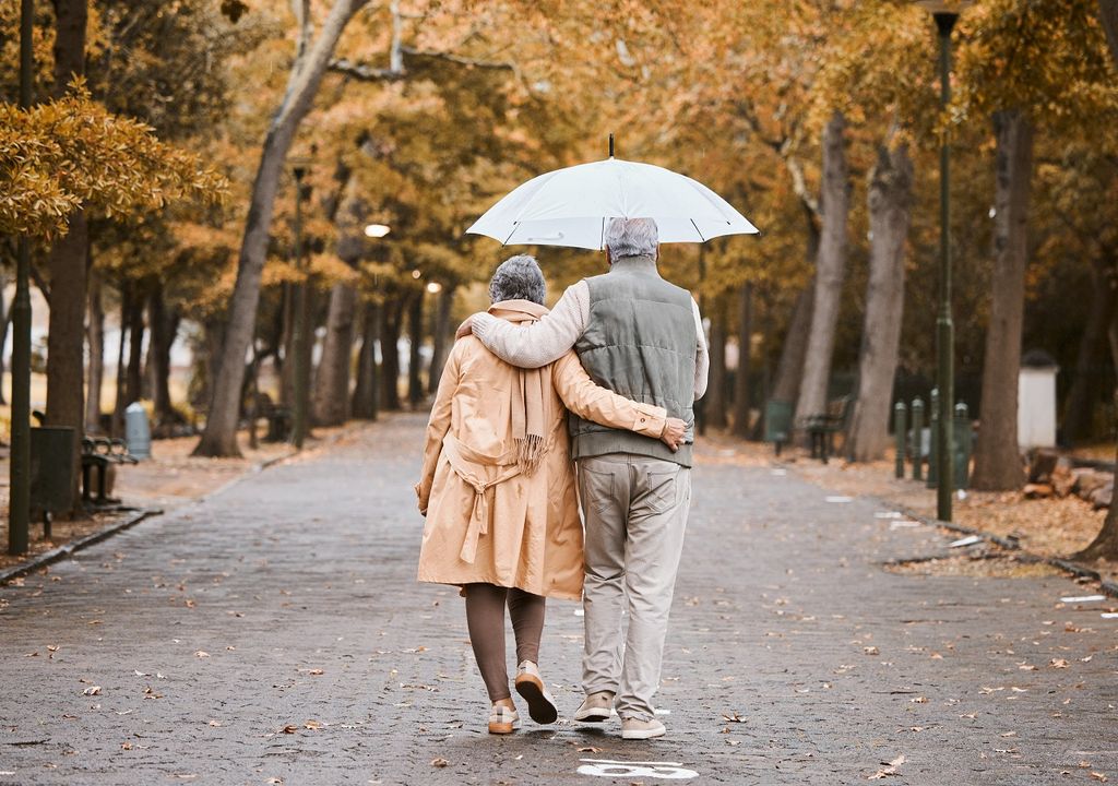 Personas caminando en un parque con paraguas; otoño; frío