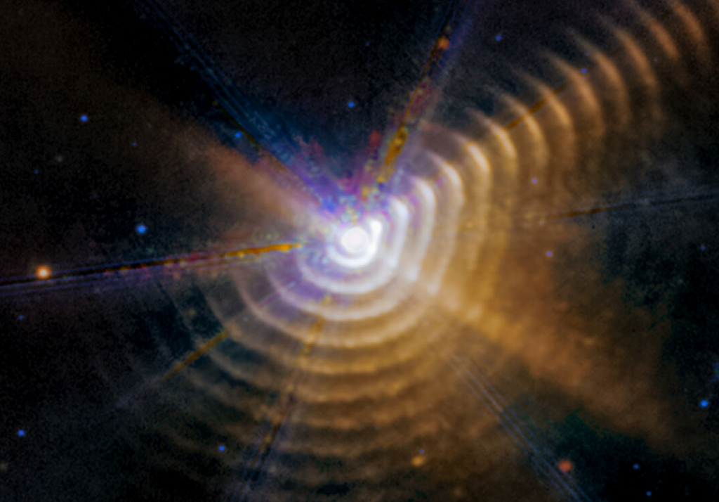 Nelle fasi finali di vita, le stelle soffiano via grandi quantità di polveri arricchendo così di elementi sempre più pesanti l'Universo. Credit: NASA/ESA/CSA