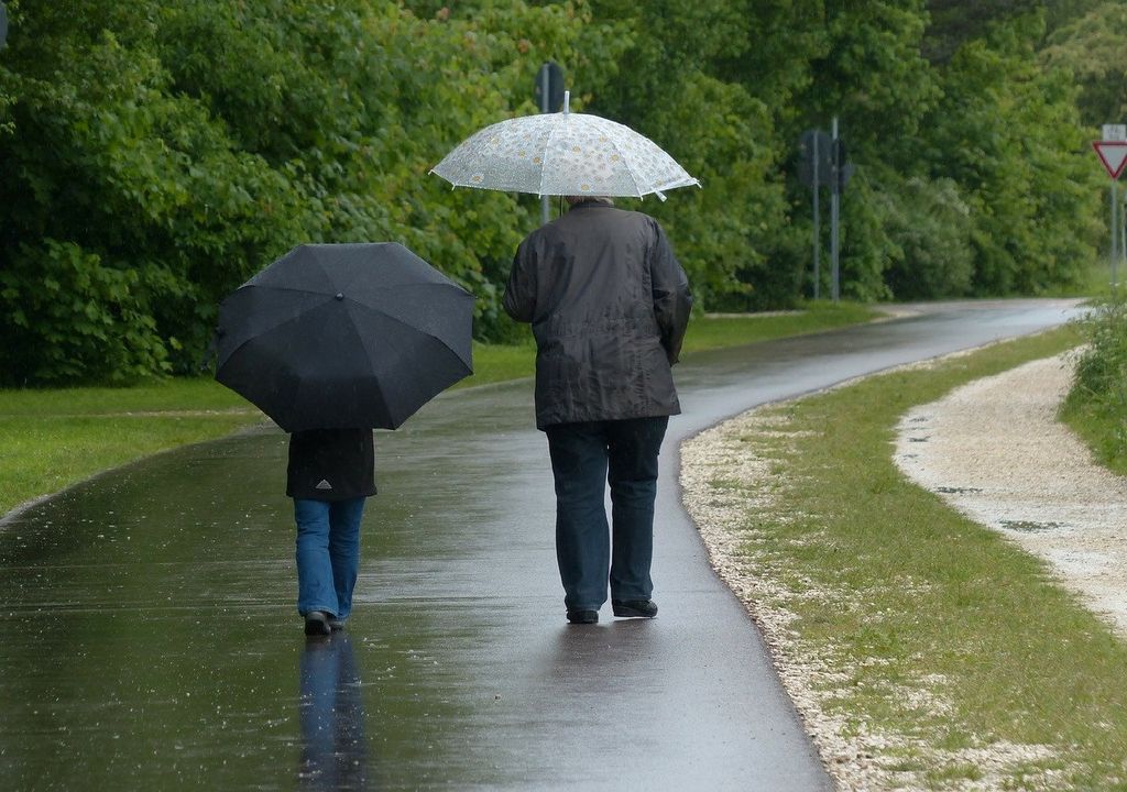 Padre e hijo caminando bajo la lluvia con paraguas