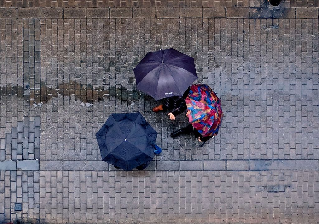 personas de paraguas paseando en una calle mojada por la lluvia. personas de paraguas paseando en una calle mojada por la lluvia.