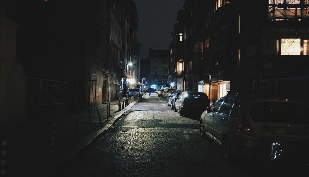 Ambiente urbano noturno com rua iliminada e carros estacionados A remoção estratégica do asfalto e do cimento é vital para as cidades combaterem as ilhas de calor. Foto: donterase via Pixabay