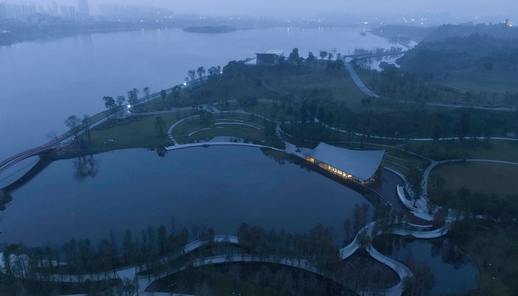 La silueta del edificio acompaña las curvas del terreno y parece flotar sobre la superficie del lago Xinglong. Crédito: MUDA Architects y Arch Daily