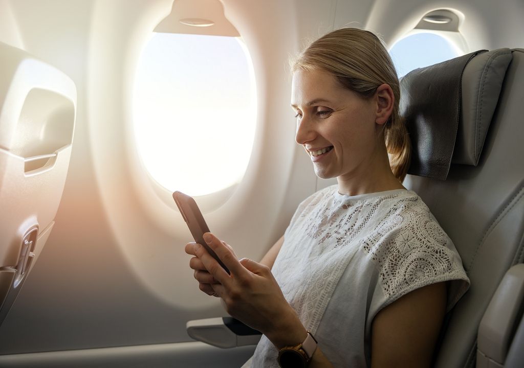 Mujer mirando su celular en un avión