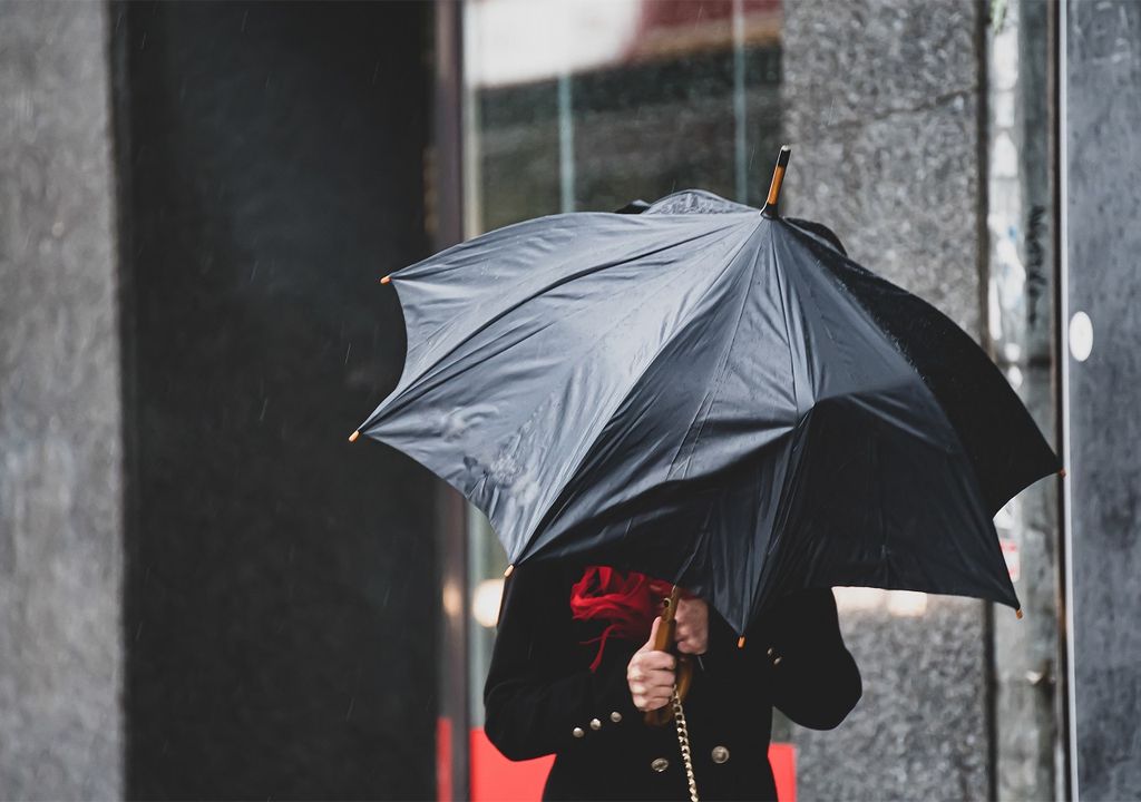 persona protegiéndose del viento y lluvia con paraguas