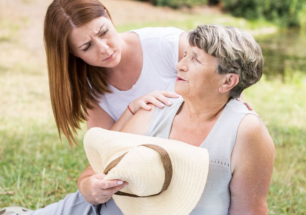 persona joven prestando ayuda a una persona de la tercera edad gobiada por las altas temperaturas