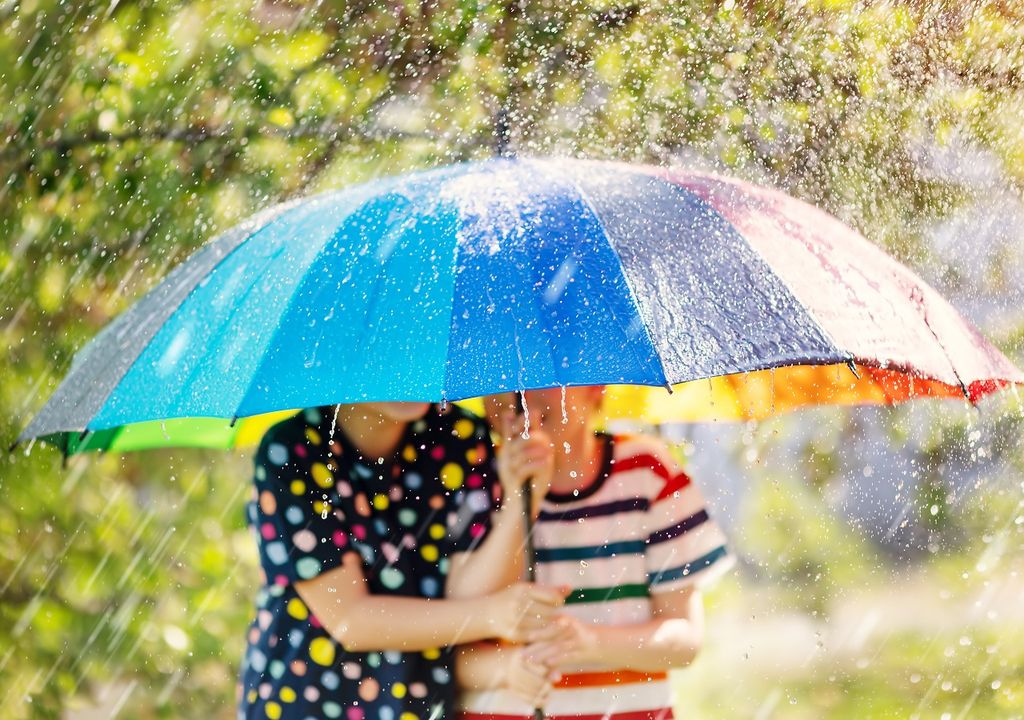 niños bajo un paraguas colorido en un día de lluvia y Sol