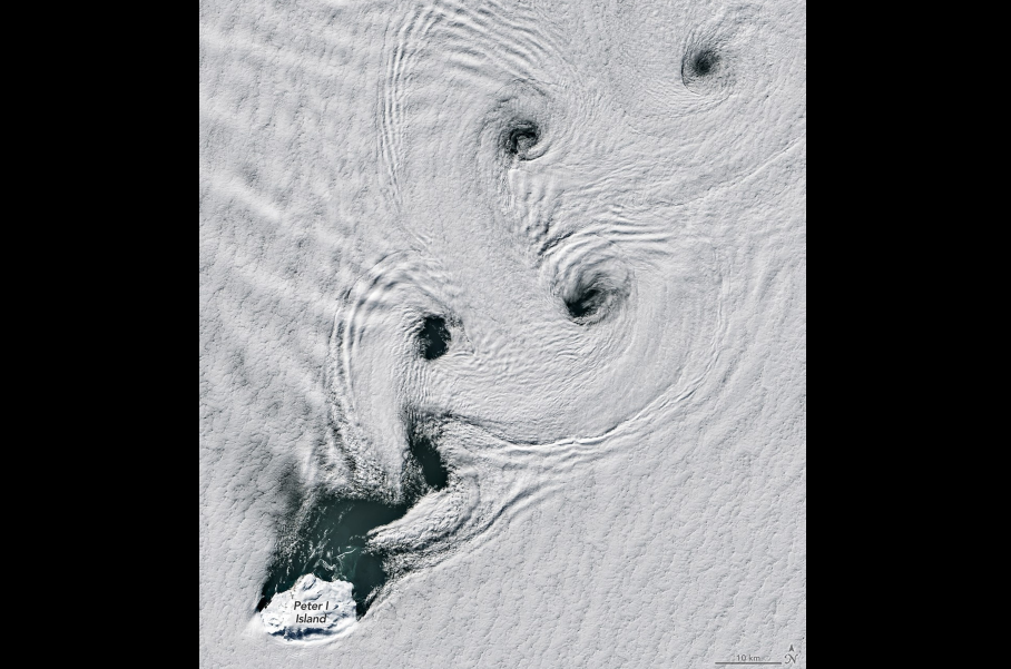 Líneas paralelas de vórtices de nubes aparecen a sotavento de una pequeña isla cubierta de hielo. En esta imagen, adquirida con el sensor OLI (Operational Land Imager) del satélite Landsat 8 el 11 de febrero de 2026, se observan calles de vórtices de Von Kármán en el lado de sotavento de la isla Pedro I. NASA/Michala Garrison