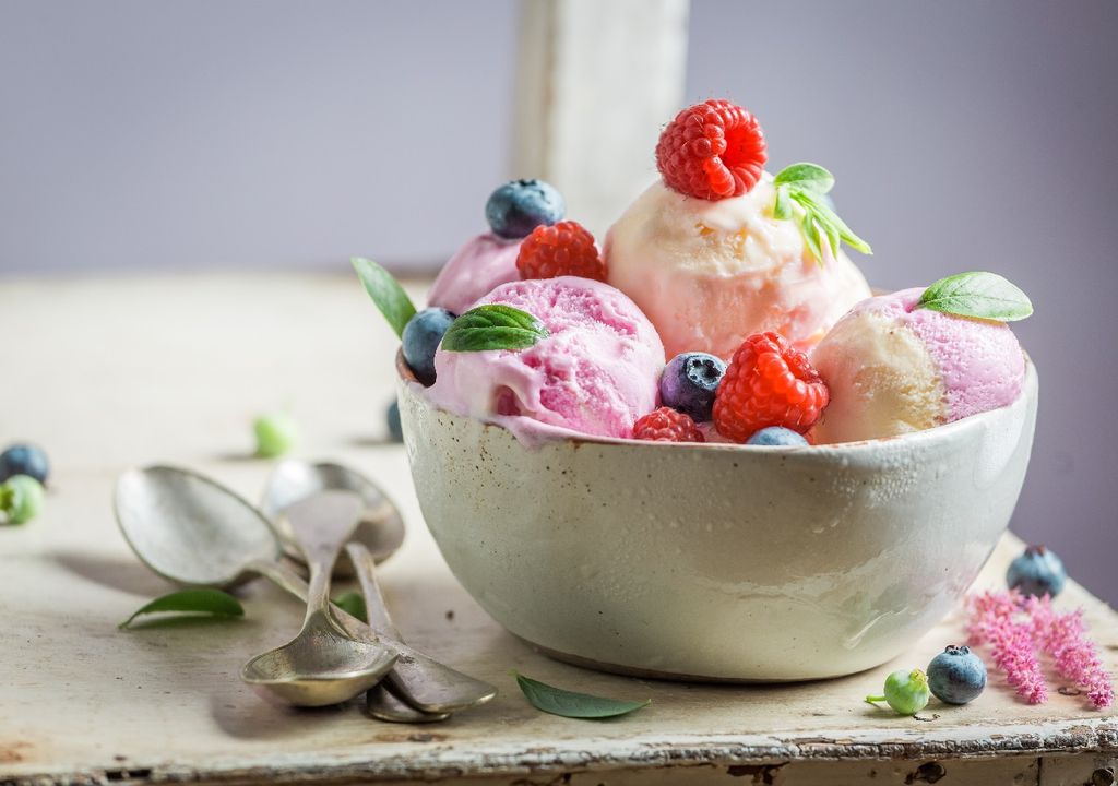 Copa de helado con frutos rojos sobre mesa de madera Copa de helado con frutos rojos sobre mesa de madera