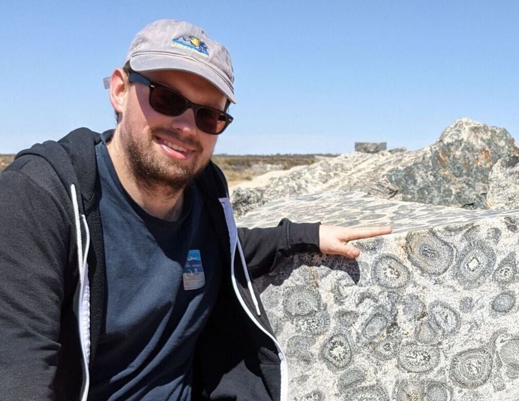 Dr. Maximilian Dröllner neben einem anderen seltenen Gestein namens Orbicularit.