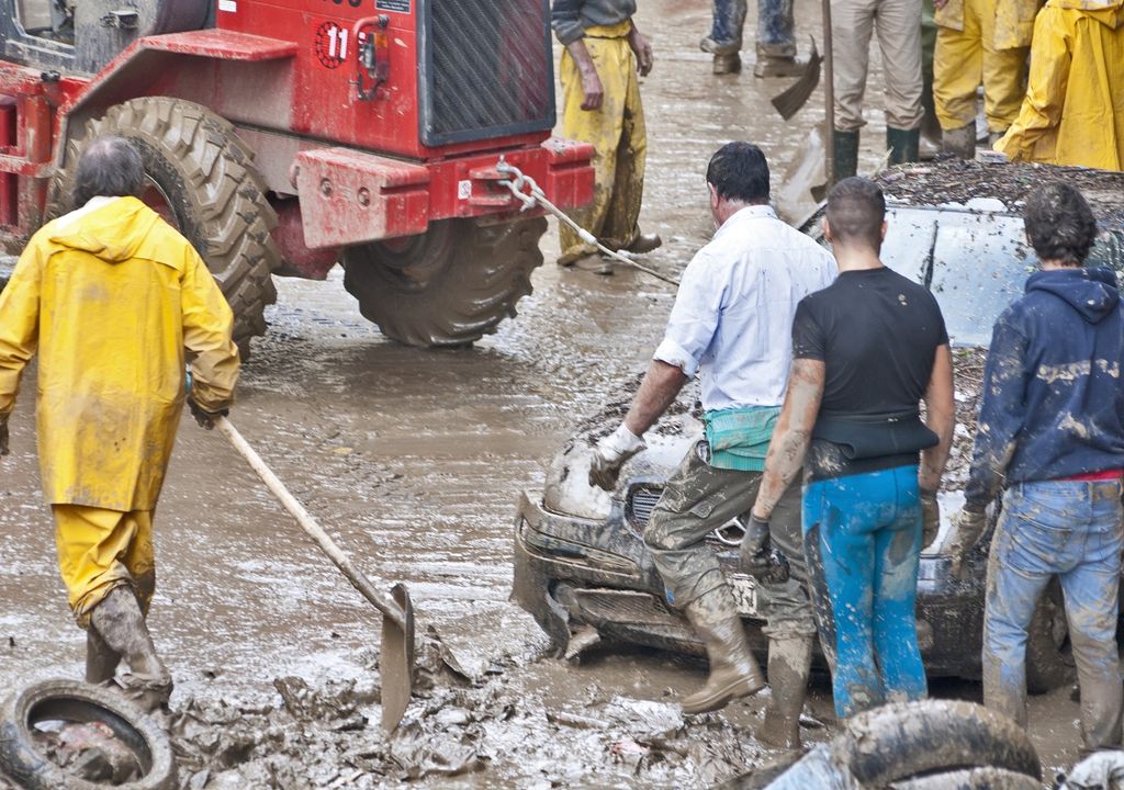 Personas rescatando un vehículo después de aluvión