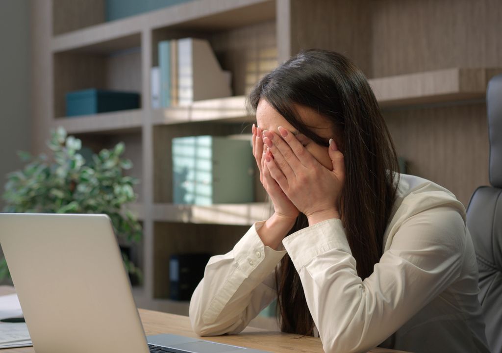 persona frente al computador, cubriéndose el rostro con las manos persona frente al computador, cubriéndose el rostro con las manos