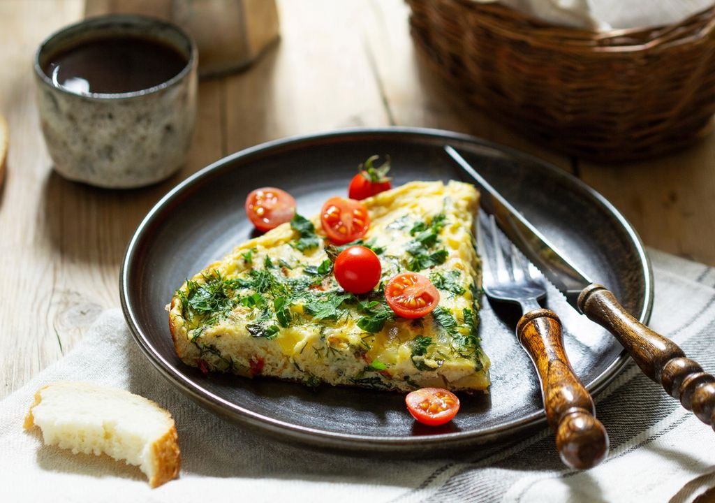 tortilla de acelga con tomates cherry presentado en plato oscuro con cubiertos fondo de mesa tortilla de acelga con tomates cherry presentado en plato oscuro con cubiertos fondo de mesa