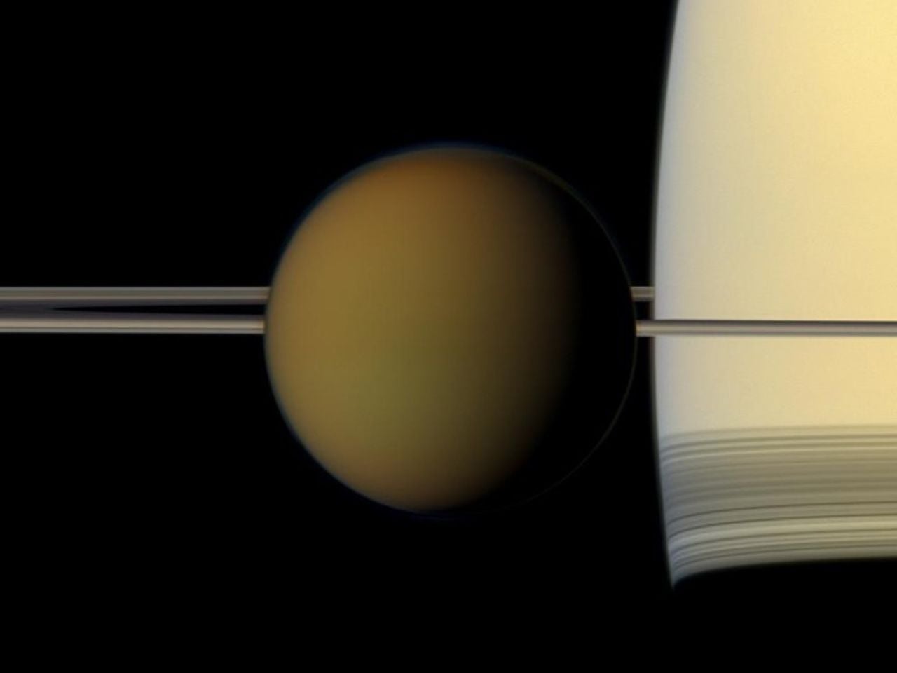 Titán, pasa frente al planeta y sus anillos en esta instantánea en color real. Crédito: Cassini / NASA.
