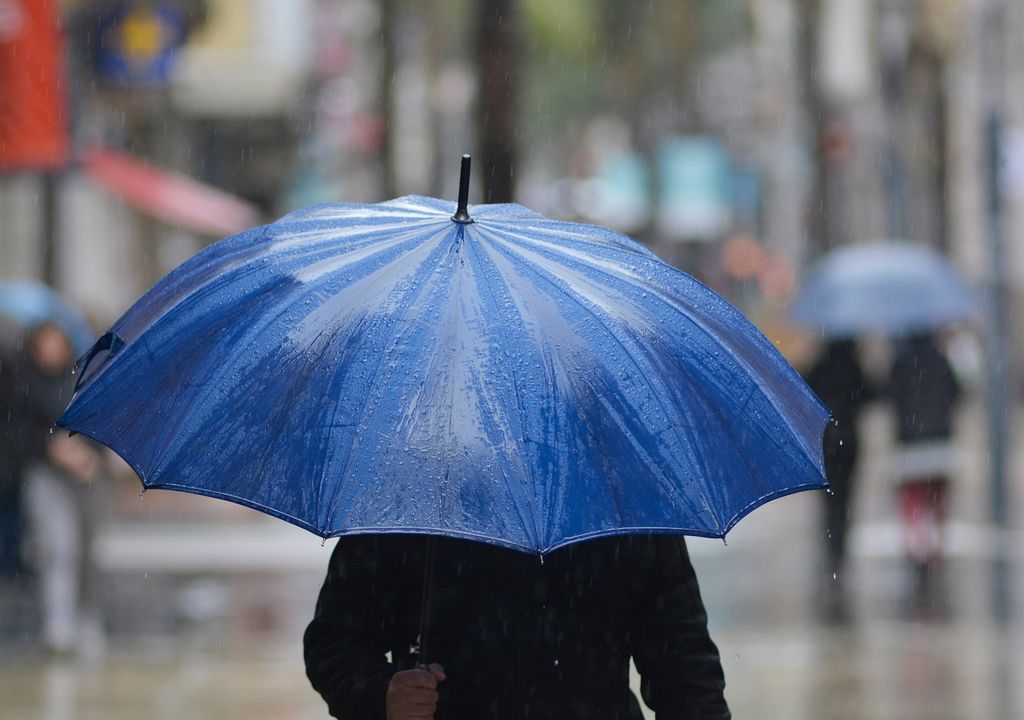 Persona caminando con un paraguas azul