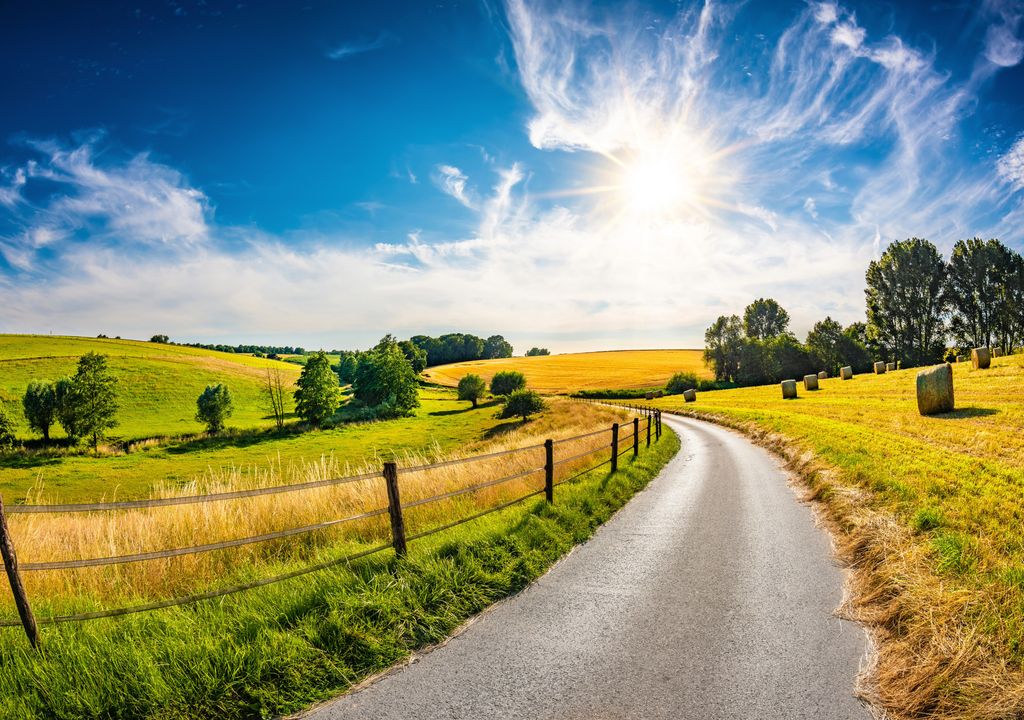 Eine Straße führt durch die hüglige Landschaft irgendwo in Deutschland, irgendwann im August