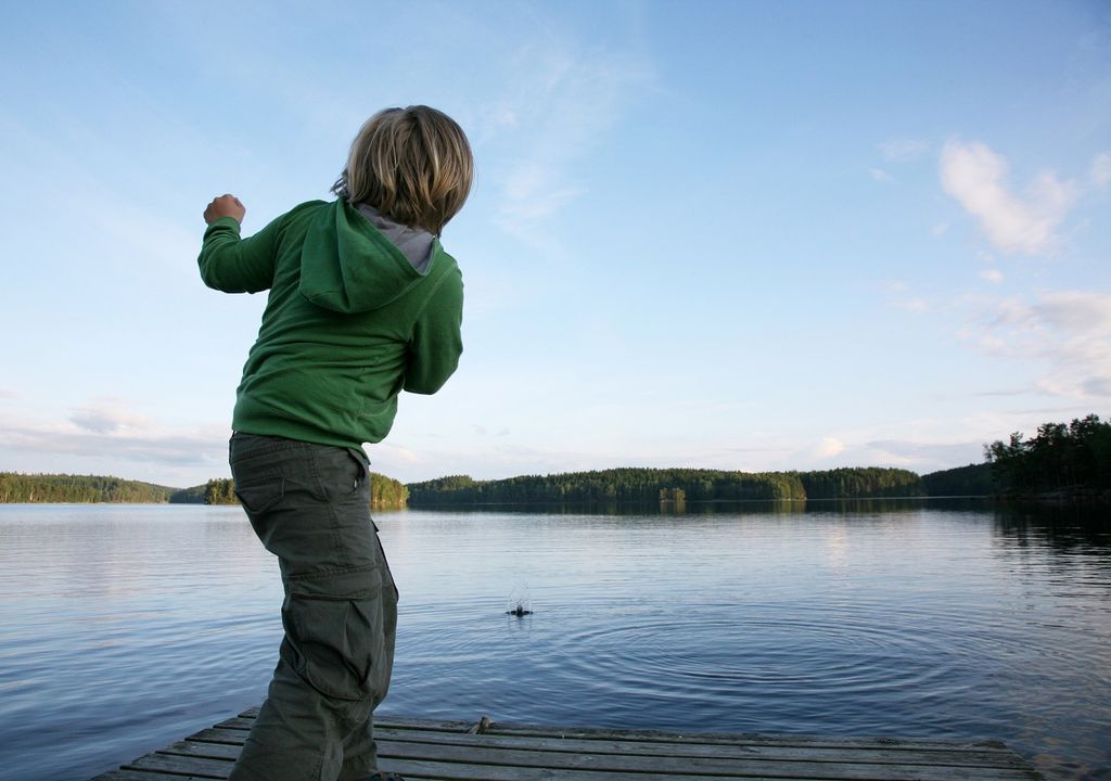 Niño tirando piedras a un lago Niño tirando piedras a un lago