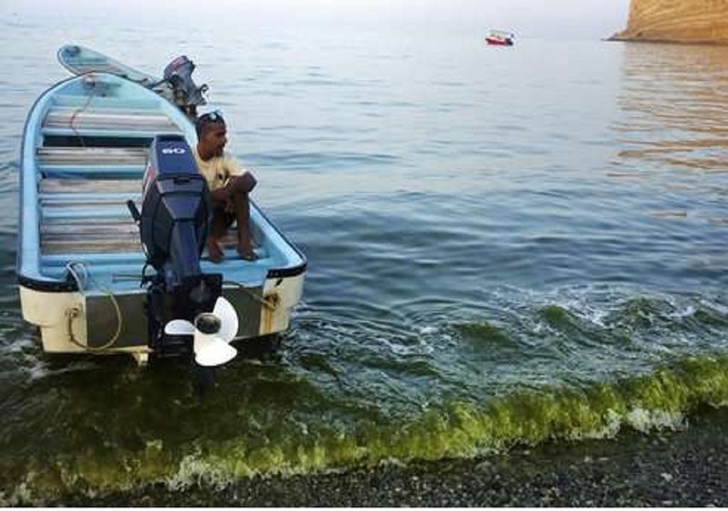 homem em lancha no Golfo de Omã; água verde